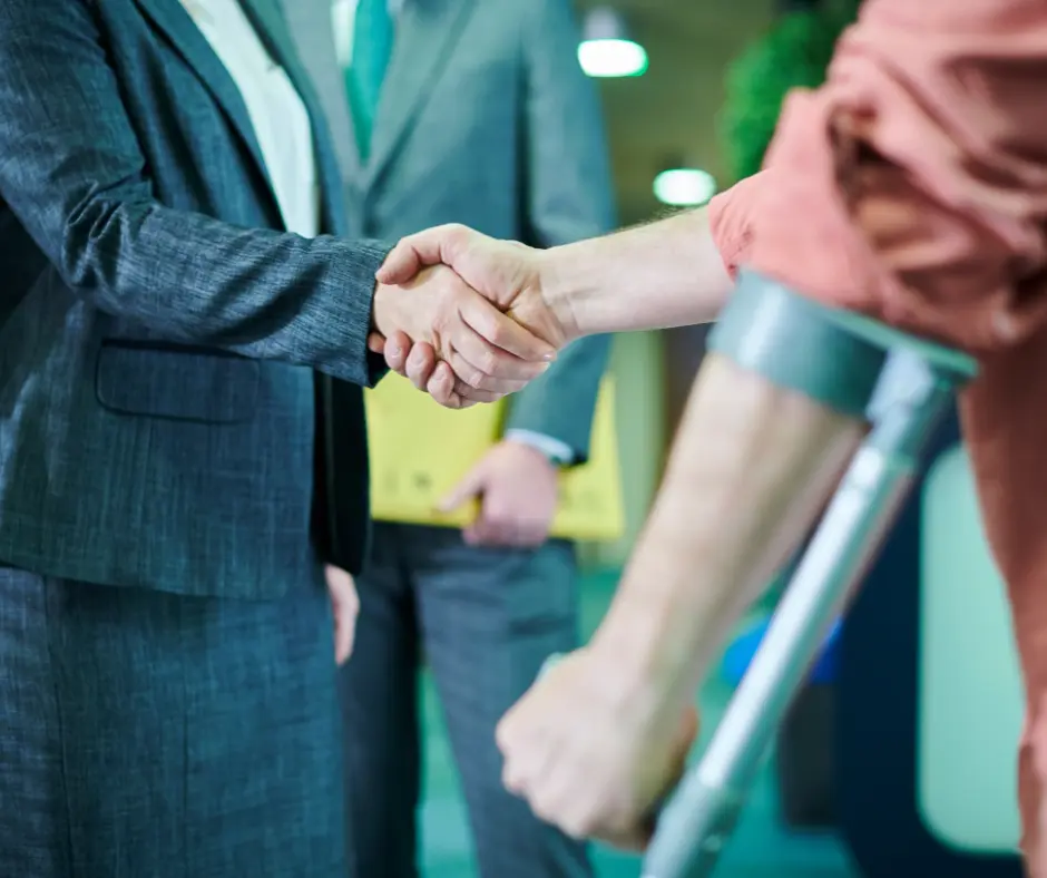 injured person on crutches shaking hands with woman in business suit
